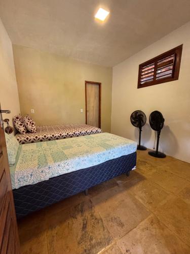 a bedroom with a bed and two black fans at Casa Girasol in Trairi