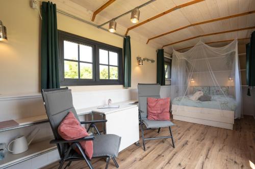 a bedroom with a bed and two chairs and a desk at Johanneshoeve - de mooiste plek op Texel in Den Hoorn