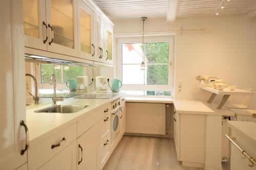 a kitchen with white cabinets and a sink and a window at Meer Weiss in Wangerland