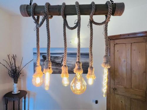 a chandelier with lights hanging from a beam at Haslemere Cottage, Beer – Coastal Getaway Near the Beach in Beer