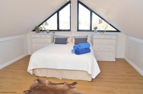 a bedroom with a white bed with windows at Riverside Lodge in Brundall