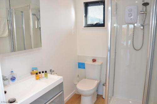 a white bathroom with a toilet and a shower at Riverside Lodge in Brundall