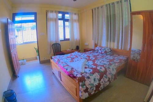 a bedroom with a bed and a desk and windows at Hotel Pelican in Kalimpong