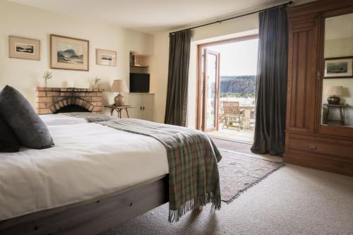 a bedroom with a bed with a fireplace and a balcony at Relugas Mill in Forres