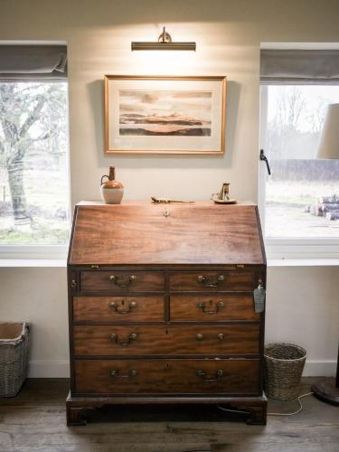 a wooden dresser in a room with two windows at Relugas Mill in Forres