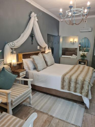 a bedroom with a large white bed and a chair at Little Rock Resort in Ladybrand