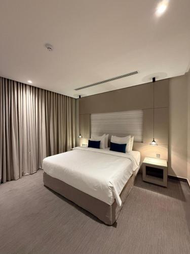 a bedroom with a large white bed and a table at Rafa Hotel Apart in Riyadh