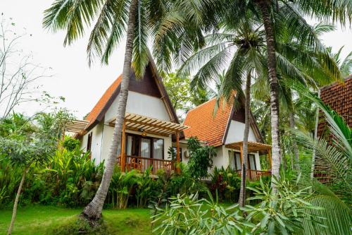 a house with palm trees in front of it at Green Coco Suite by AGATA in Nusa Penida