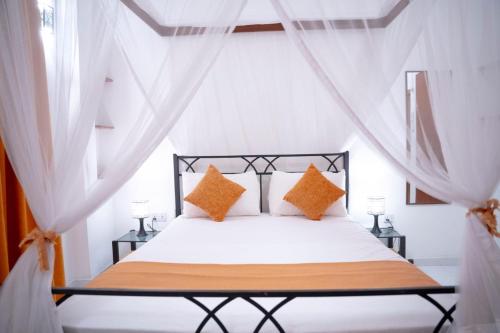 a bedroom with a white bed with orange pillows at Zeleny Apartments in Nugegoda
