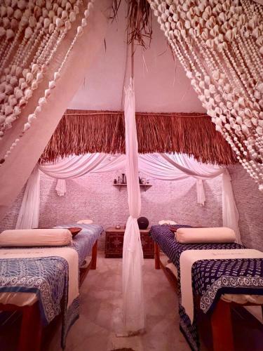 a room with three beds and a ceiling with curtains at Pachamama Pool Villa in Gili Islands