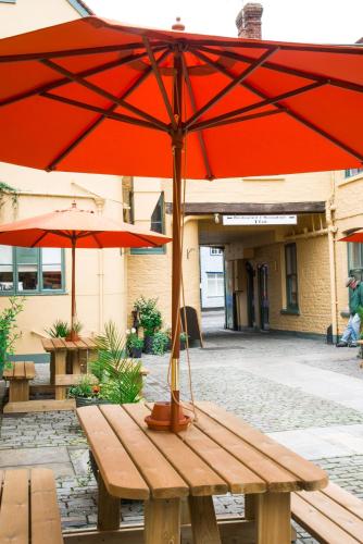 a wooden picnic table with an umbrella on it at The Dolphin Hotel in Wincanton