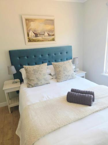 a bedroom with a large bed with a blue headboard at Coral Cottage in Struisbaai
