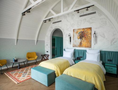 two beds in a room with a painting on the wall at CaspiMayr Retreat Beach Resort in Baku