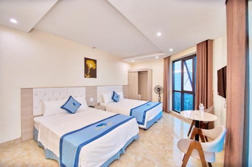 a hotel room with two beds and a table at Tuấn Đạt Luxury FLC Sầm Sơn in Sầm Sơn