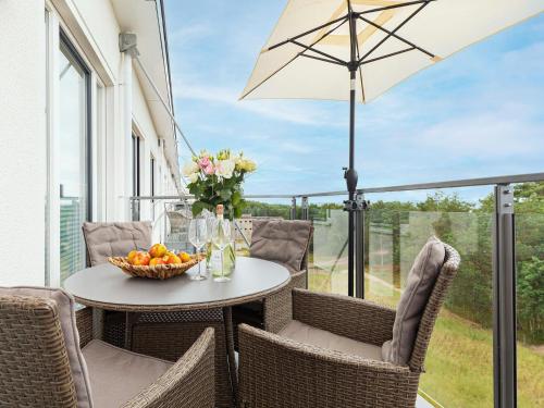 a table with a bowl of fruit and an umbrella on a porch at Prora - Dachgeschoss Wohnung mit Sauna - Sky Lodge in Binz