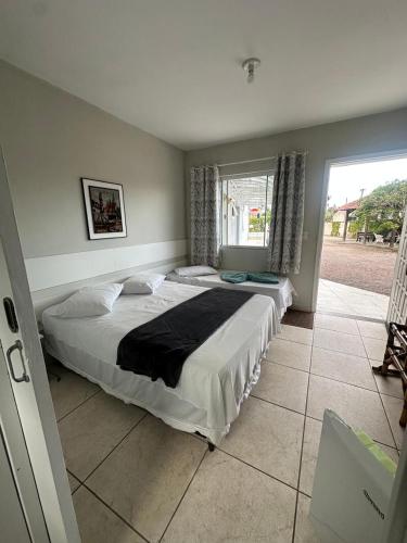 a bedroom with two beds and a large window at Pousada Guanumbi in Morretes