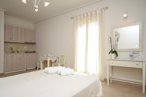 a white bedroom with a white bed and a kitchen at Perla Hotel in Agios Prokopios