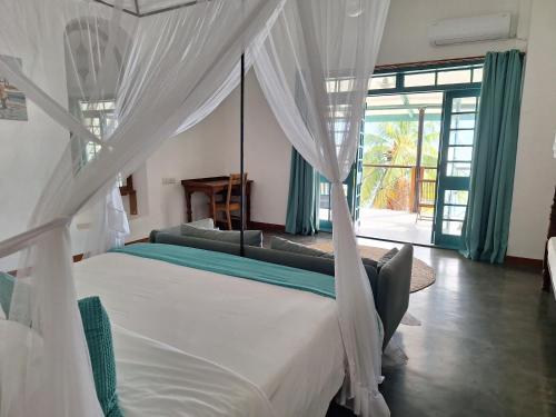 a bedroom with a canopy bed with a couch at The Archipelago Waterfront in Zanzibar City