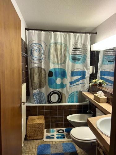 a bathroom with a shower curtain and a toilet at Disentis-Mustér Ski Apartment in Disentis