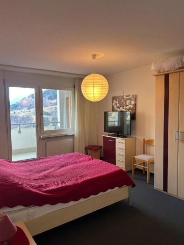 a bedroom with a red bed and a television at Disentis-Mustér Ski Apartment in Disentis