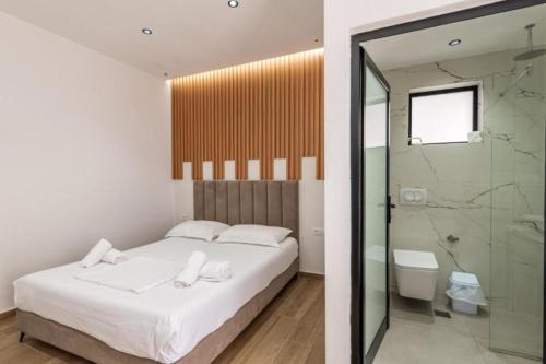 a bedroom with a white bed and a shower at Azure Bay Resort in Sarandë