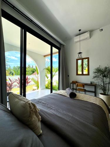 a bedroom with a large bed with a large window at Casa De Made - Villas in Jembrana