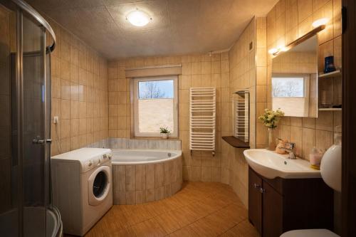 a bathroom with a tub and a sink and a washing machine at Hostel Arkobaleno sieci Mazowia Hostels Group in Marki