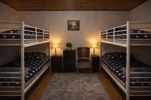 a bedroom with three bunk beds and a chair at Hostel Arkobaleno sieci Mazowia Hostels Group in Marki