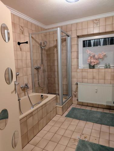 a bathroom with a tub and a shower and a window at Apartment Kadenbach in Kadenbach