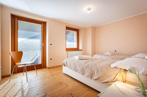 a bedroom with two beds and a chair and a window at La Marmote Albergo Diffuso di Paluzza Aip in Paluzza