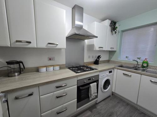a kitchen with white cabinets and a stove top oven at Cozy Gem Luxury House in Marston Green