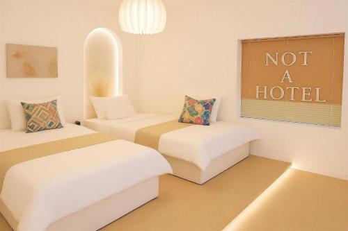 a room with two beds and a sign that says not a hotel at Jeonpo Cafe Street Near Seomyeon Entire House 2 Floors 7 Guests in Busan