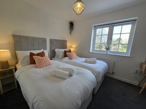 two large beds in a room with a window at Cozy Gem Luxury House in Marston Green