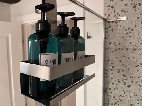 a shelf with three bottles of soap in a bathroom at Roma284 Apt Centro in Piacenza