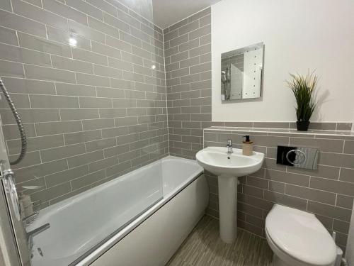 a bathroom with a tub and a sink and a toilet at Cozy Gem Luxury House in Marston Green