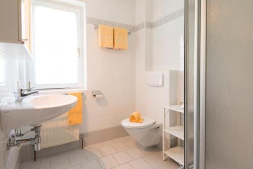 a white bathroom with a sink and a toilet at Golfappartements in Bad Gastein