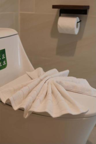 a pile of white towels sitting on top of a toilet at Rungarun Residence in Ratchaburi