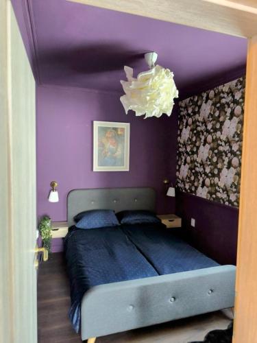 a bedroom with a bed with purple walls and a chandelier at Apartments Sabo in Kraljevica