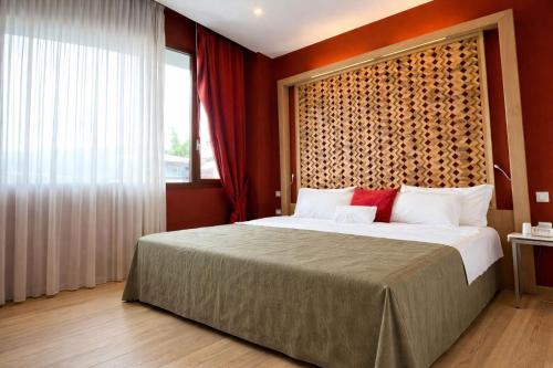 een slaapkamer met een groot bed en een groot raam bij Bouganville Hill Resort & Wellness Space in Picerno