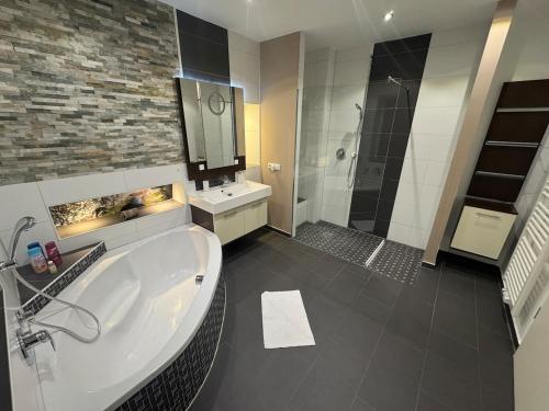 a bathroom with a tub and a sink and a shower at BOHO Suite Tierra nähe Salzburg in Freilassing
