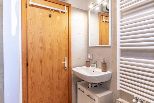 a bathroom with a sink and a wooden door at Trilo Ciasa Brìma in Carano