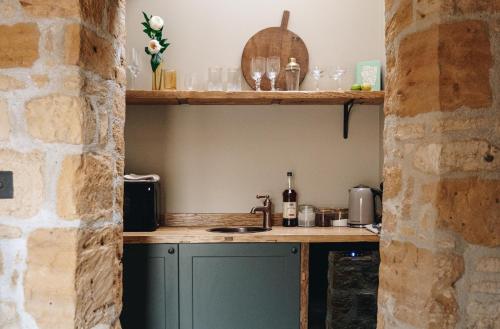 a kitchen with a green cabinet in a stone wall at The Library in Moreton in Marsh