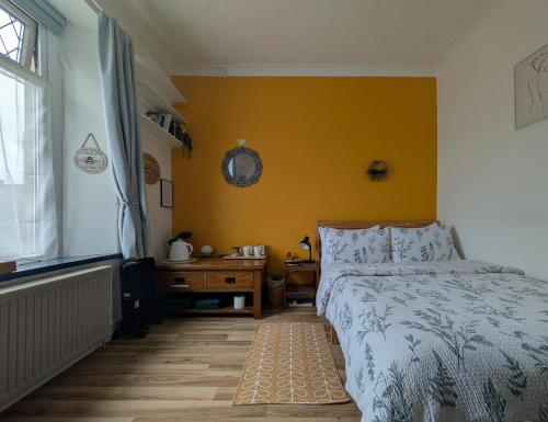 a bedroom with a bed and a yellow wall at R1 - Bright Quiet Double - City & Beach Access, WIFI, Free Parking, Bus Stop 50ft From House - Self Catering in Swansea