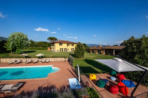 a pool with chairs and an umbrella next to a house at Villa Farmi by MMega in Bibbiena