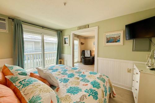 a bedroom with a bed and a tv and a balcony at Saltwater Breeze in Wells