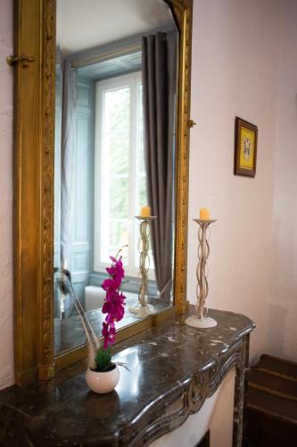 a mirror on top of a table with flowers on it at Château de MontSablé in Lezoux