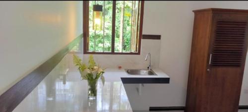 a bathroom with a sink and a vase with flowers in it at Vidisa Villas in Hikkaduwa