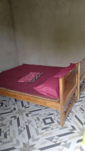 a wooden bed with purple sheets on top of a floor at Vitthala rukmini in Gokarna