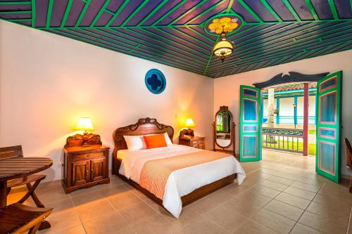 a bedroom with a bed and a table at Decameron Las Heliconias - All Inclusive in Quimbaya