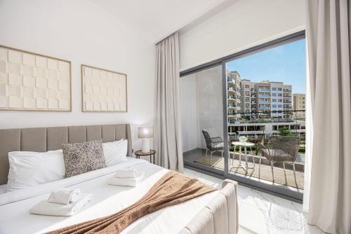 a bedroom with a bed and a large window at Chic 2BR Haven in Prime Location in Gardenia Living in Dubai